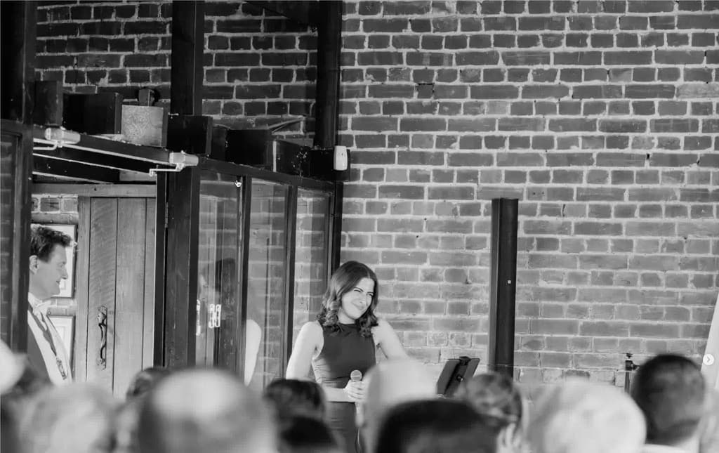 Singing at Cooling Castle Barn — black and white photograph with the wedding breakfast looking on