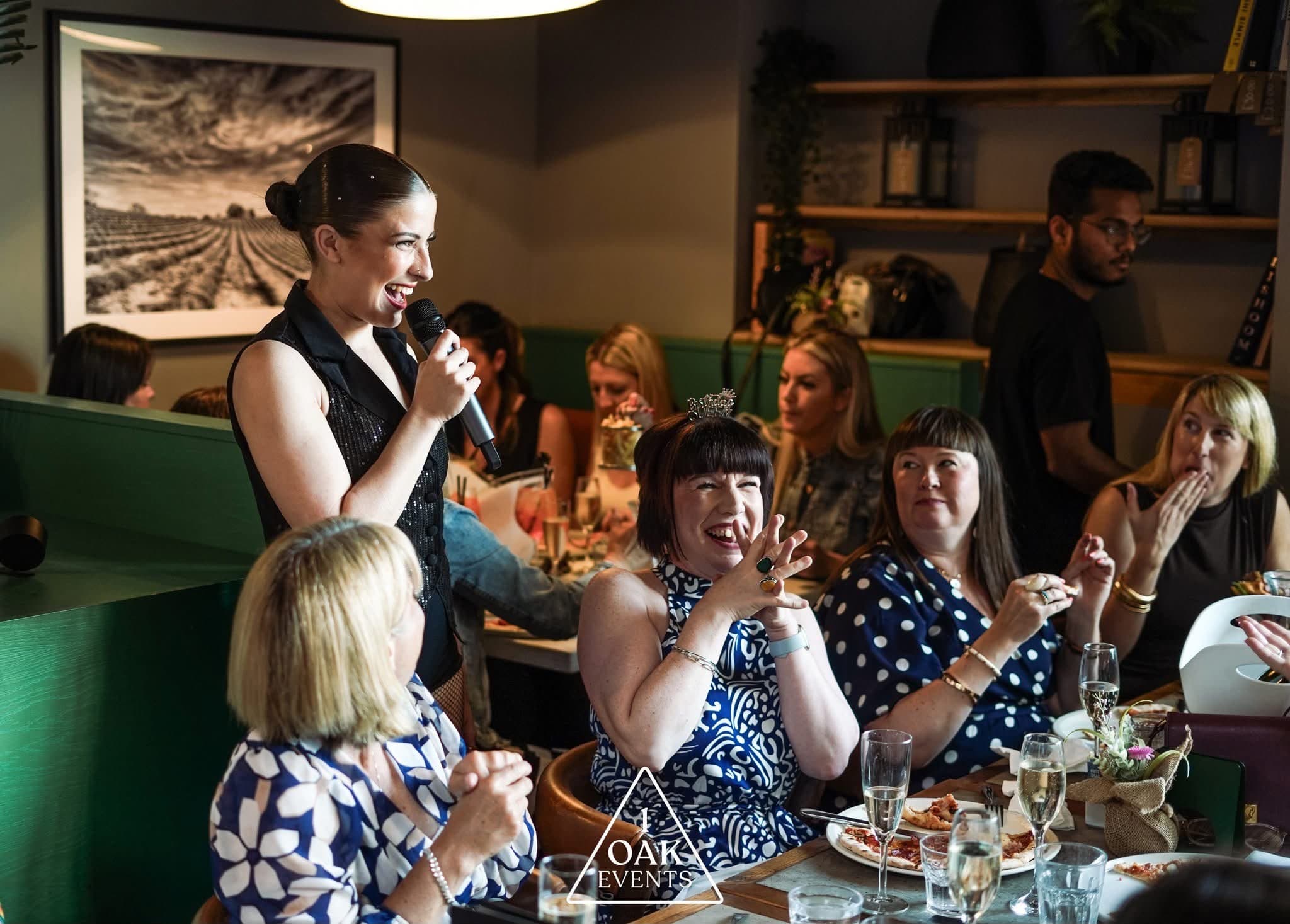 Singing a live party set beside a table of guests — pizza, fizz, and the room singing back